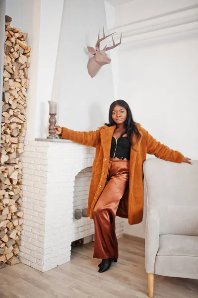Elegante mujer afroamericana en abrigo naranja posado en la habitación agai — Foto de Stock