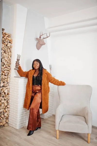 Elegante mujer afroamericana en abrigo naranja posado en la habitación agai — Foto de Stock
