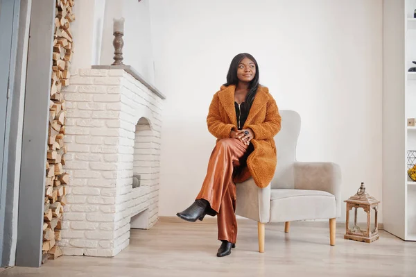 Elegante mujer afroamericana en abrigo naranja posado en la habitación agai — Foto de Stock