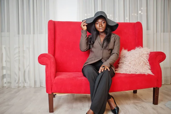 Elegante mujer afroamericana en ropa formal y sombrero sentado en — Foto de Stock