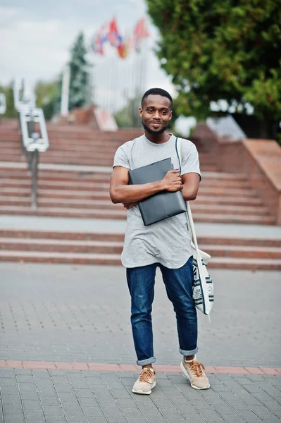 African student male posed with backpack and school items on yar