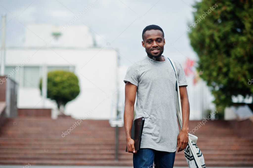African student male posed with backpack and school items on yar