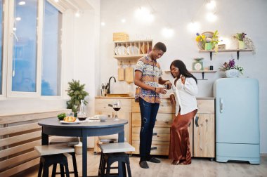 Afro-Amerikan sevgililer mutfakta şarap içiyorlar.