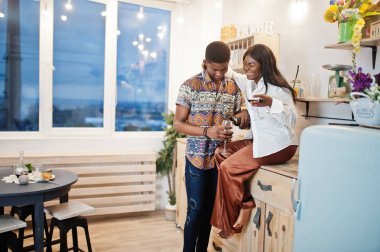 Afro-Amerikan sevgililer mutfakta şarap içiyorlar.