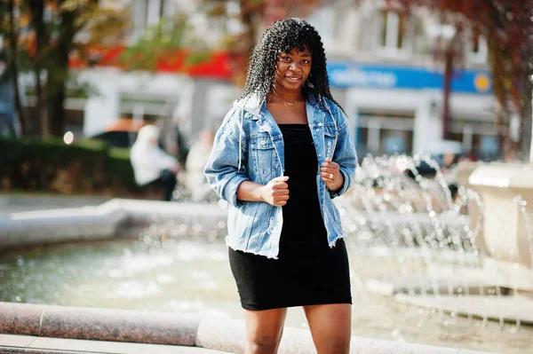 Стильная трэнди-афро-французская кудрявая женщина позировала в осенний день в джинсах — стоковое фото