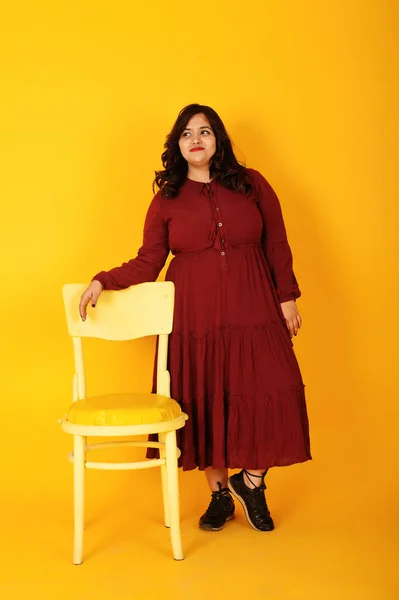 Attractive south asian woman in deep red gown dress posed at stu