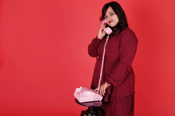 Attractive south asian woman in deep red gown dress posed at stu