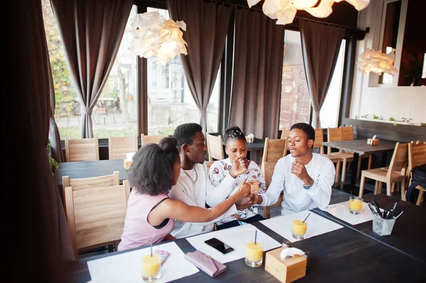 Happy african friends sitting and chatting in cafe. Group of bla