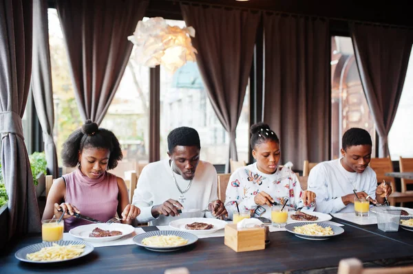 Amigos africanos felizes sentados, conversando no café e comendo comida. Gr — Fotografia de Stock