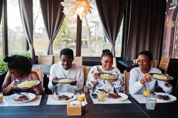 Amigos africanos felizes sentados, conversando no café e comendo comida. Gr — Fotografia de Stock