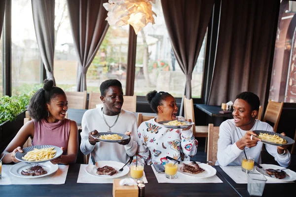 Amigos africanos felizes sentados, conversando no café e comendo comida. Gr — Fotografia de Stock