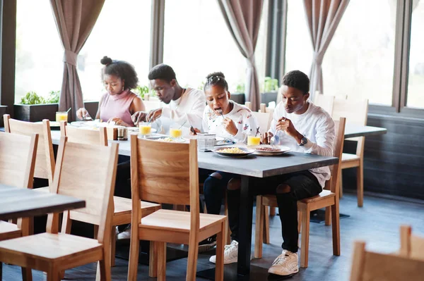 Glückliche afrikanische Freunde sitzen, im Café plaudern und essen. gr — Stockfoto