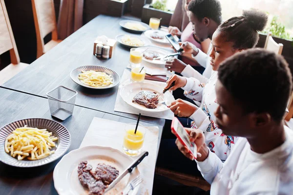Glückliche afrikanische Freunde sitzen, im Café plaudern und essen. gr — Stockfoto