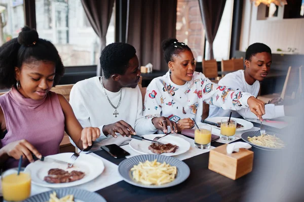 Amigos africanos felizes sentados, conversando no café e comendo comida. Gr — Fotografia de Stock