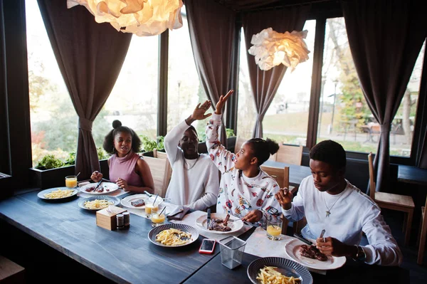 Amigos africanos felizes sentados, conversando no café e comendo comida. Gr — Fotografia de Stock