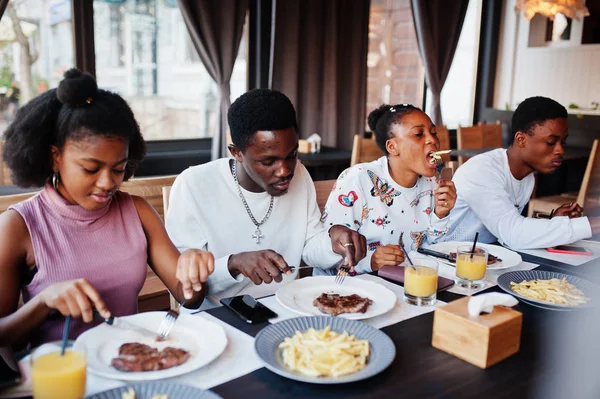 Amigos africanos felizes sentados, conversando no café e comendo comida. Gr — Fotografia de Stock