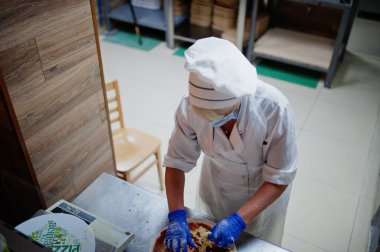 Pizzacıda çalışan koruyucu maskeli bir pizzacı..