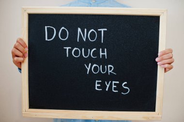 Gözlerine dokunma. Coronavirus konsepti. Çocuk tahtaya yazı yazmış..