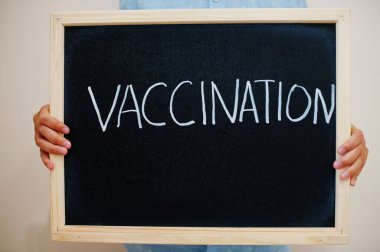 Aşılama. Coronavirus konsepti. Çocuk tahtaya yazı yazmış..