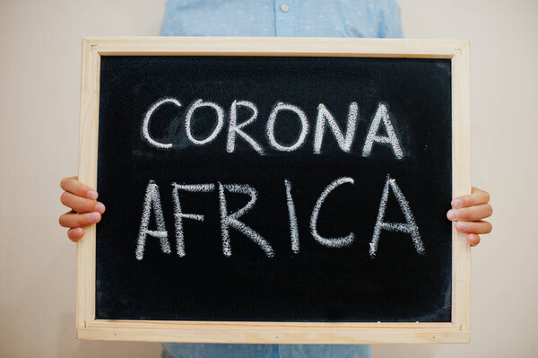 Корона Африка. Концепция коронавируса. Мальчик держит надпись на доске.