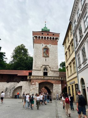 Krakow, Polonya - 08 Temmuz 2025 Krakow 'da kaldırımlı sokakları ve aşağıda yürüyen insanları olan bir ortaçağ kulesi