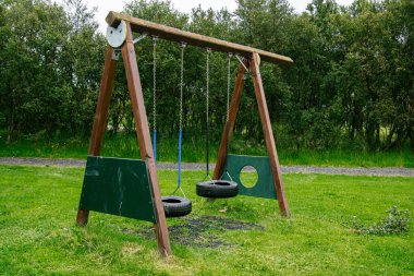 İzlanda 'nın yemyeşil bir parkında, tekerlekleri koltuk olan tahta bir salıncak.