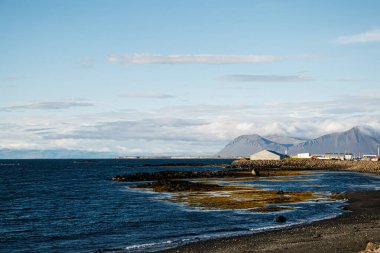 Okyanus ve kayalık İzlanda 'da berrak bir gökyüzünün altındaki uzak dağlar.