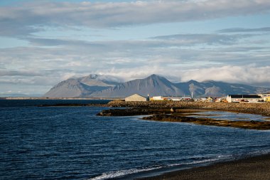 Uzak dağlar, okyanus ve İzlanda 'nın huzurlu köy manzaralı güzel kıyı şeridi..