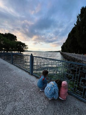 Çocuklar, sakin bir günbatımı anında manzaranın tadını çıkarıyorlar..