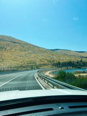 Hırvatistan 'ın Primosten kentinde güneşli bir yamaç ve sakin bir denizin yanında pitoresk bir yol kıvrılıyor.