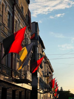 Gün batımı ışığı ve canlı atmosferi olan kentsel binalarda renkli Ukrayna bayrakları.