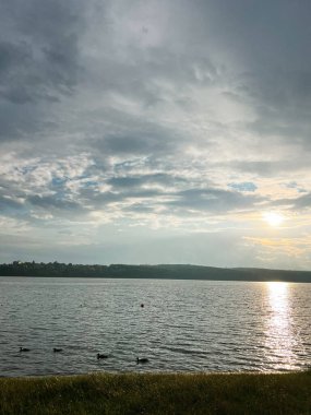 Gün batımında göl manzaralı Ördekler yüzüyor ve tepeler uzaklarda