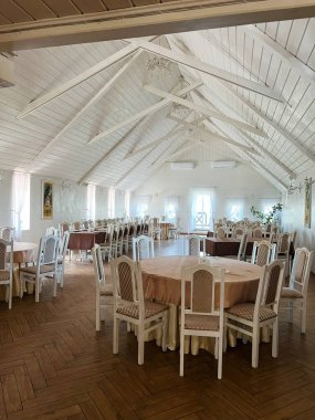 Geniş, aydınlık ziyafet salonu yuvarlak masalar, ahşap döşemeler ve rahat bir ortam..