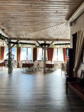 Lokantanın içi masalar, sandalyeler, kapalı mekanlar ve ahşap aksanlarla aydınlık.