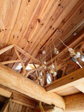 Ilık aydınlatma, güzel işlenmiş bir kırsal iç mekandaki karmaşık ahşap işçiliğini aydınlatır.