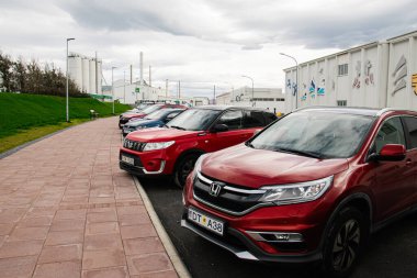 Akranes, İzlanda - 06 Eylül 2025: Akranes, İzlanda 'da bulutlu bir gökyüzünün altındaki sanayi binalarının yakınındaki birkaç park edilmiş araba