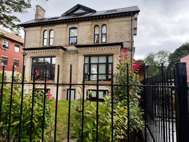 Manchester, İngiltere - 11 Eylül 2025: Modern özellikli, bahçe ve çitlerle çevrili geleneksel tuğla ev.