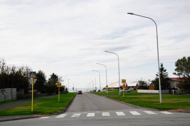 Akranes, İzlanda 'da sakin bir cadde. Tabela, yeşillik ve bulutlu gökyüzü çerçeveli.