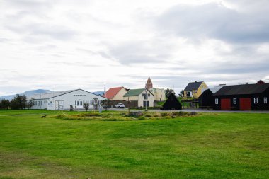 Akranes, İzlanda - 12 Eylül 2025: Akranes, İzlanda 'da yeşil alanlar ve geleneksel binalar, bulutlu bir gökyüzü altında, Safnasklinn halk müzesi.