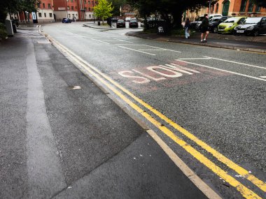 Manchester, İngiltere - 14 Eylül 2025: Manchester kentsel caddesi yavaş markalaşma ve yol kenarındaki arabalarla.