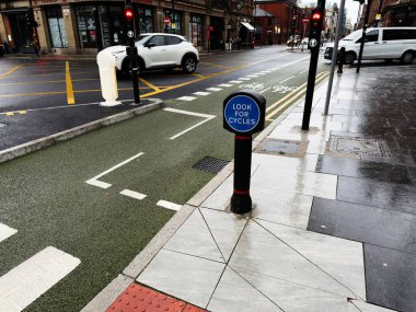 Manchester, İngiltere - 14 Eylül 2025: Manchester, İngiltere 'de şehir trafiğinin ortasında ıslak kaldırım ve bisiklet yolu.