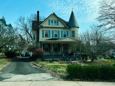 Jenkintown, Pennsylvania, ABD - 01 Nisan 2025: Taret, garaj yolu ve bahçeli klasik ev ağaçlarla çevrili banliyö manzaralı