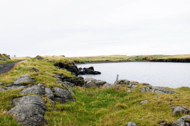 İzlanda 'nın kıyı kesimindeki kayalık kıyıların ve sakin suların huzurlu manzarası.