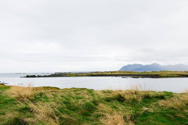 Gölü, uzak dağları ve bulutlu koşulları olan güzel İzlanda kırsalları.