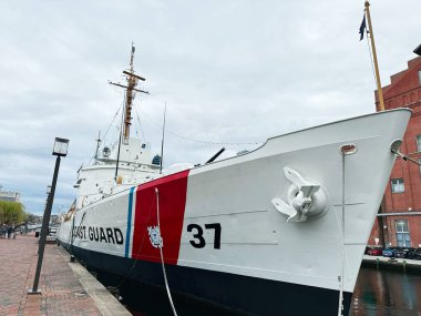 Baltimore, Maryland, ABD - 10 Nisan 2025: Manzaralı bir limana yanaşmış büyük bir sahil güvenlik gemisinin detaylı görüntüsü.