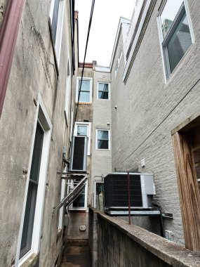 Philadelphia, Pennsylvania, ABD - 28 Nisan 2025: Havalandırma üniteleri ve görünür kabloları olan ABD 'deki yüksek binalar arasındaki dar sokak.