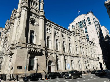 Philadelphia, Pennsylvania, ABD - 29 Nisan 2025: Büyük Mimari Masonik Tapınağı ve açık mavi gökyüzü Dışarıda park etmiş arabalarla dolu büyük bir şehir caddesi.