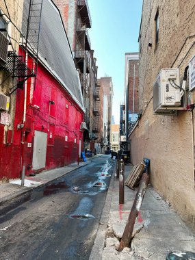 Philadelphia, Pennsylvania, ABD - 29 Nisan 2025 Philadelphia 'da kırmızı duvarları, yangın merdivenleri, su birikintileri ve parlak mavi gökyüzü olan bir ara sokak.
