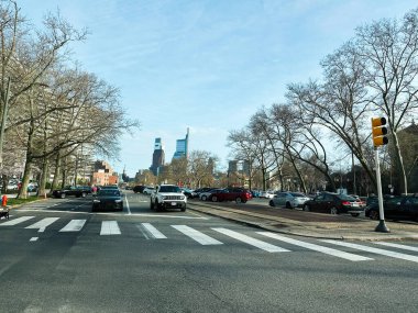 Philadelphia, Pennsylvania, ABD - 29 Nisan 2025 Yaya geçidi, hareketli arabalar ve açık mavi gökyüzü altında uzak bir ufuk çizgisi.