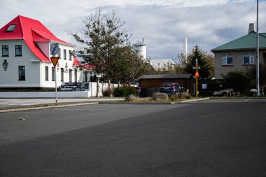 Akranes, İzlanda - 17 Eylül 2025: Akranes 'te manzaralı bir sokak manzarası kırmızı çatılı, işaretli ve park halindeki arabalarla.